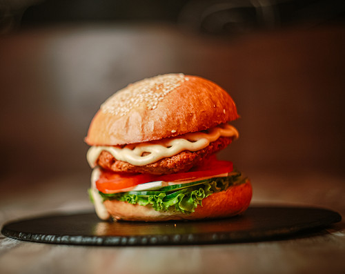 AVE Burger — Микс салатов цезарь и греческий между двумя горячими булочками. Курица в панировке, помидоры, свежий огурчик,  лист салата, сыр фета и соус цезарь.
